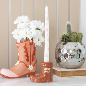 Brown Cowboy Boot Candle Holder with floral taper candle on a shelf.