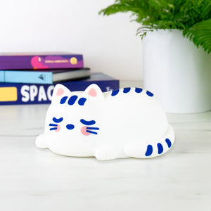 Side view of Catnap Lamp on a desk next to books and a plant – perfect for kids’ rooms or cosy spaces.