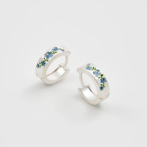 Front angle view of Fable Forget Me Not Silver Mini Hoop Earrings with hand-painted blue enamel flowers on matte silver hoops.