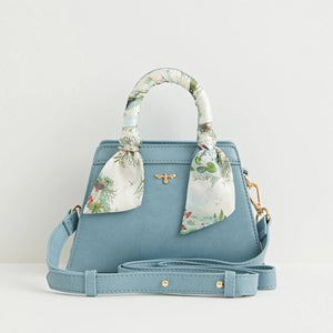 Front View: A structured blue mini tote bag made from recycled faux leather, featuring a silk-twilly scarf-wrapped handle and a gold-tone Fable England bee emblem.