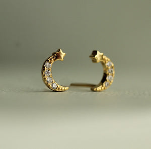 Close-up of gold vermeil moon and star stud earrings with crystal accents on a neutral background.