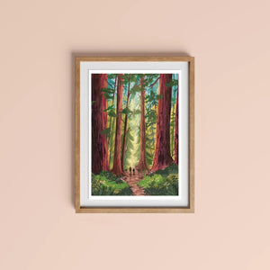 Into the Trees Version 2 art print A4 by Charis Raine Illustration framed on wall, featuring giant redwood trees and woodland path.