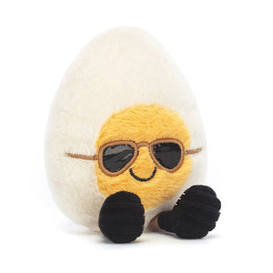 A charming plush egg toy from Jellycat called Amuseable Boiled Egg Chic. It has a soft, smooth eggshell exterior in a fetching shade of pale yellow and plump, egg-shaped body. The toy has large, expressive sunglasses and a cheerful smile, which makes it irresistible to cuddle and adore.