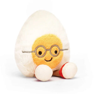 Cream-and-yellow Jellycat Egg Geek plush, turned slightly, showcasing its quirky charm and chocolate cord legs.