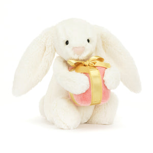 At An Angle: A peek at the playful side of Jellycat Bashful Bunny with its signature long ears and a mysterious wrapped gift.