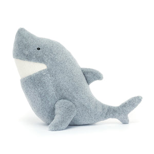 Swimming with joy! Jellycat Silvie Shark, a cuddly grey plush toy with a toothy smile, displays its soft fins and permanently happy tail.