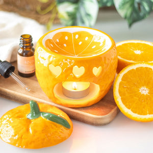 Front view of bright orange ceramic oil burner with round opening and curved top dish for wax melts or essential oils.