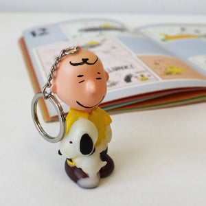 Close-up of Peanuts Charlie Brown & Snoopy Light-Up Keyring next to a Peanuts comic book.
