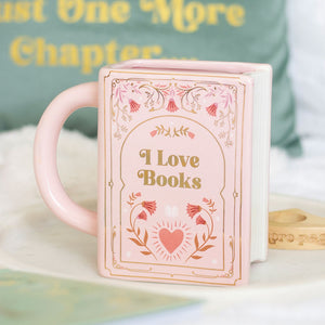 Pink ceramic book shaped mug with “I Love Books” text and floral design, styled on a tray.