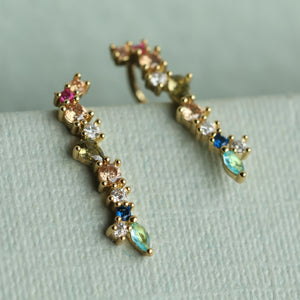 Macro view of rainbow earrings highlighting the fine detailing of the multicoloured stones and gold-plated sterling silver setting.