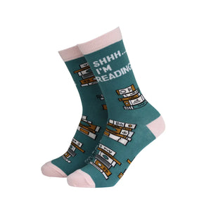 Pair of teal and pink bamboo socks with “Shhh… I’m Reading” text and book stack design, shown on angled display.
