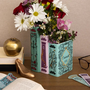 Steel Mill & Co Triple Book Vase with flowers – Ceramic vase shaped like three classic fairy tale books, filled with fresh flowers on a desk.