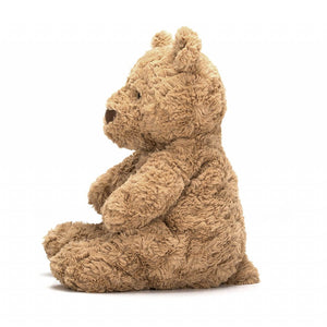 Jellycat Bartholomew teddy bear covered in soft brown fur. Sitting to the side with his arms and legs stretched out.