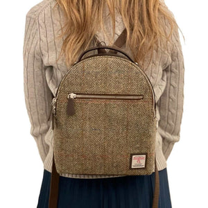 Lady wearing a Maccessori Harris tweed backpack with a green and brown herringbone pattern.
