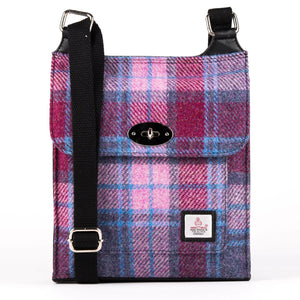 Harris Tweed satchel bag in a pink and blue check tartan design with the adjustable shoulder strap draped across the top.