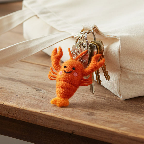 Handmade red felt lobster keyring with stitched details on white background