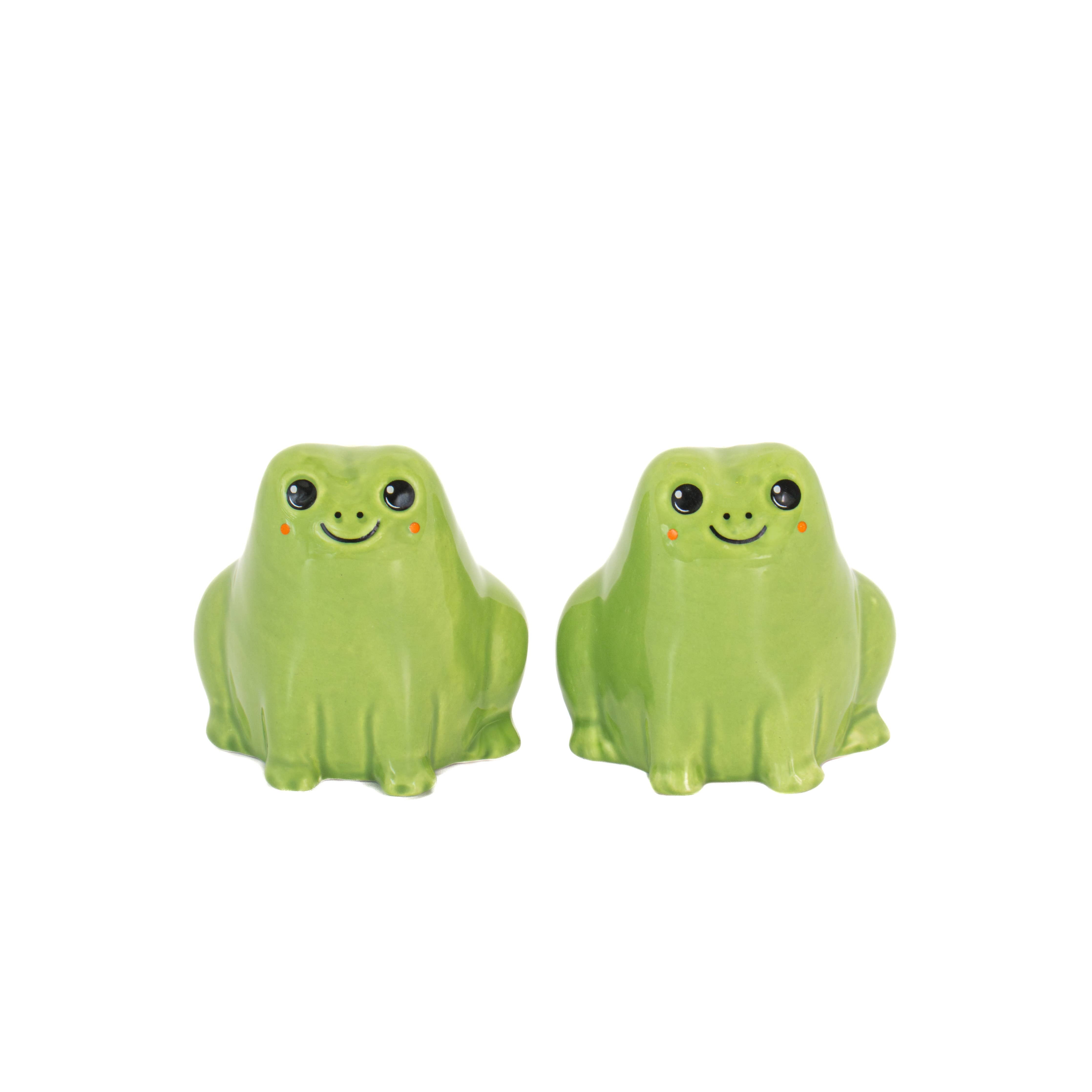 Pair of green ceramic frog salt and pepper shakers with rosy cheeks on white background