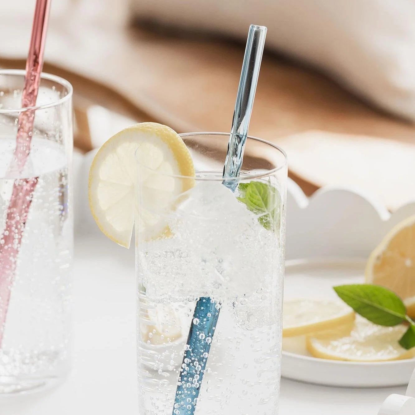 Blue twist glass straw in sparkling drink with lemon slice.