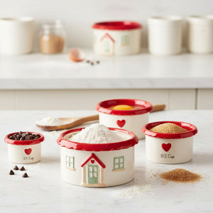 Set of house-shaped ceramic measuring cups with red and white design stacked together