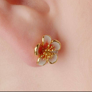 Apple blossom stud earring with white enamel petals and coral centre shown on skin