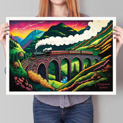 Person holding an unframed A3 art print of the Glenfinnan Viaduct with the Jacobite Steam Train, featuring a vibrant, colourful Highland landscape.