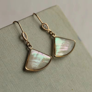 Another close-up of Abalone Pearl Fan Earrings – A pair of gold-plated earrings with fan-shaped mother-of-pearl inlays, set against a soft green fabric background, highlighting their shimmer and vintage aesthetic.