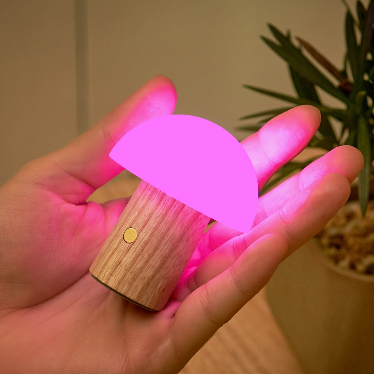 Pink glowing Alice Mushroom Lamp Super Mini held in hand with wooden base.