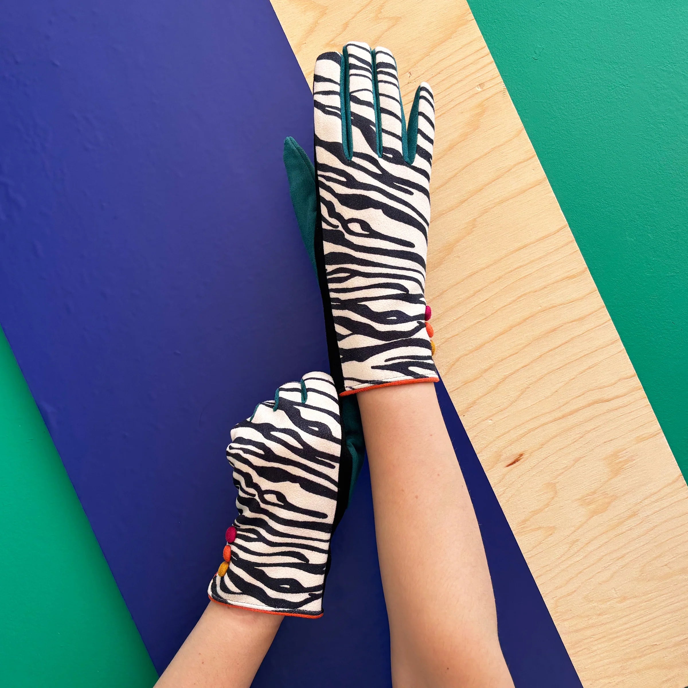 Black and white zebra print gloves with teal details and orange buttons.