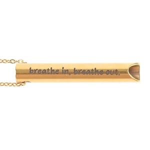 Close-up of gold breathing necklace pendant engraved with the phrase “breathe in, breathe out,” designed to reduce anxiety through focused breathing.