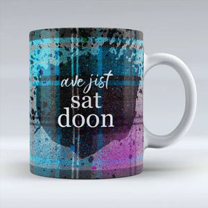 Front view of Ave Jist Sat Doon Mug with Scottish tartan design and Glasgow humour phrase.