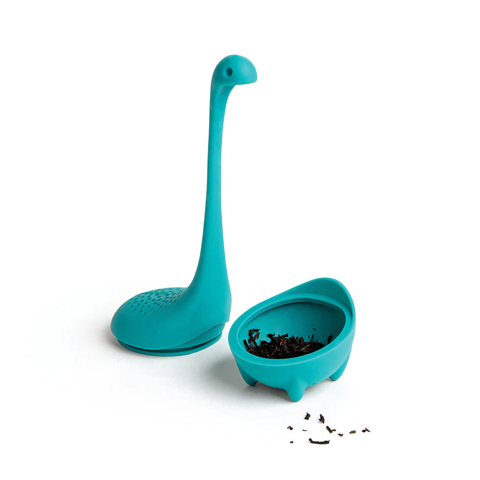 Baby Nessie tea infuser opened, showing loose tea leaves inside the bottom compartment, with the top part placed separately.