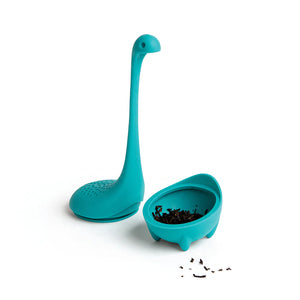 Baby Nessie tea infuser opened, showing loose tea leaves inside the bottom compartment, with the top part placed separately.