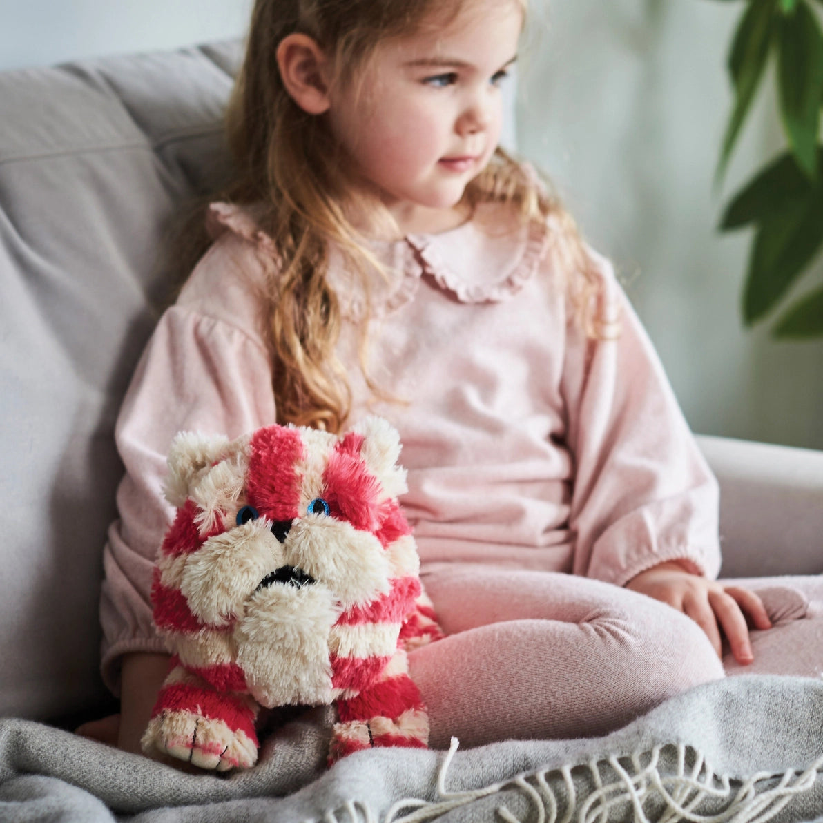 Child sitting with Warmies Bagpuss Cat plush comforter.