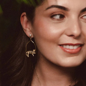 Woman wearing Bill Skinner’s Clouded Leopard Triangle Hoop Earrings and matching necklace, styled in a lush, tropical setting.