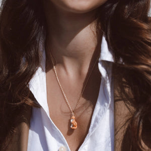 Woman wearing the Bill Skinner fox pendant necklace styled with an open white shirt and brown blazer, showing how the pendant sits on the chest.