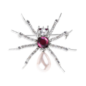 Front view of Bill Skinner Pearl Spider Brooch featuring a polished silver-toned body with crystal-encrusted legs, deep amethyst centre stone, and a teardrop pearl body on white background.
