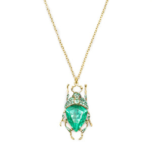 Close-up of green beetle pendant necklace with antique gold chain and crystal detailing.
