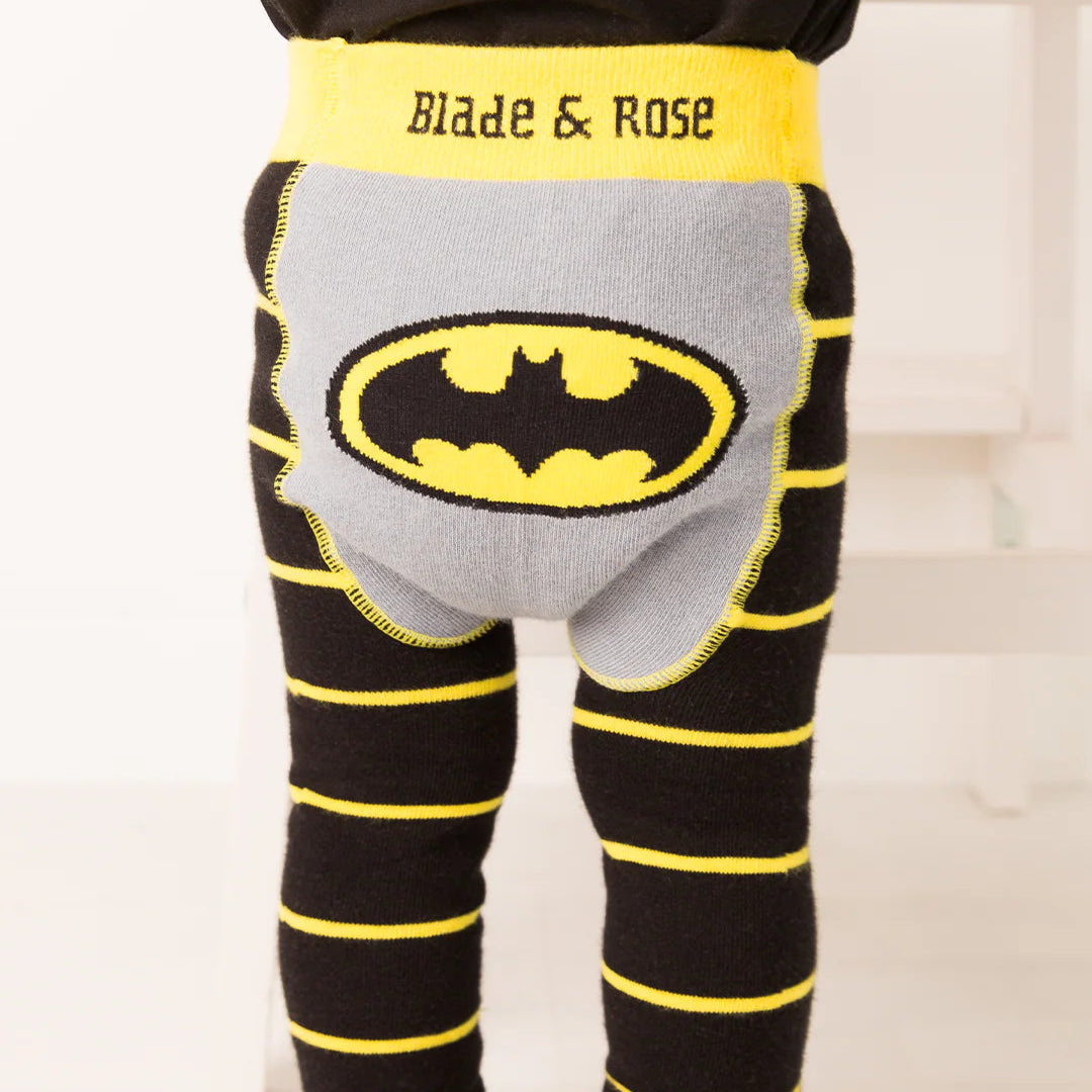  Baby standing in Blade & Rose Batman™ “Get Ready” leggings with black and yellow stripes and large Bat-signal logo on the grey bum panel.