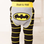  Baby standing in Blade & Rose Batman™ “Get Ready” leggings with black and yellow stripes and large Bat-signal logo on the grey bum panel.