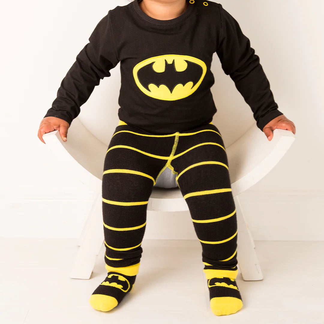 Toddler sitting wearing Blade & Rose Batman™ “Get Ready” leggings and matching Batman™ long-sleeve top with yellow Bat-signal logo.
