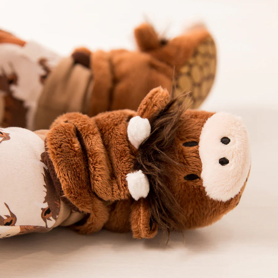 Side view of plush Neutral Highland Cow baby booties with velcro fastenings and fleece lining.