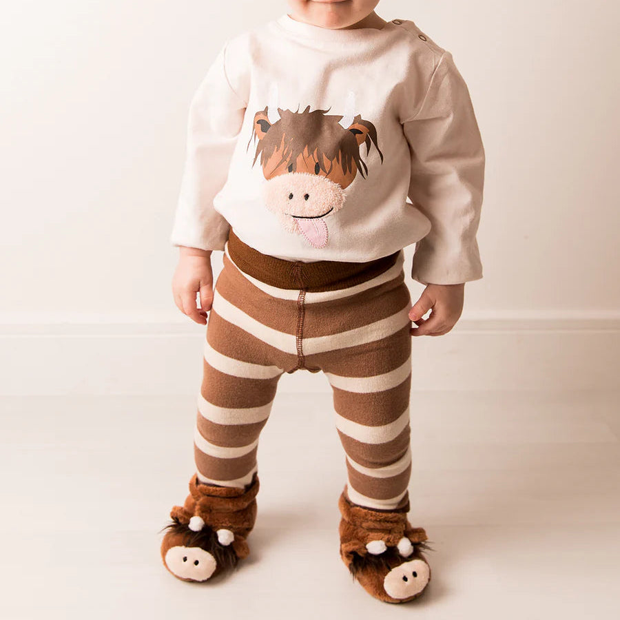 Child wearing striped leggings and Neutral Highland Cow Booties with matching long-sleeve cow top.