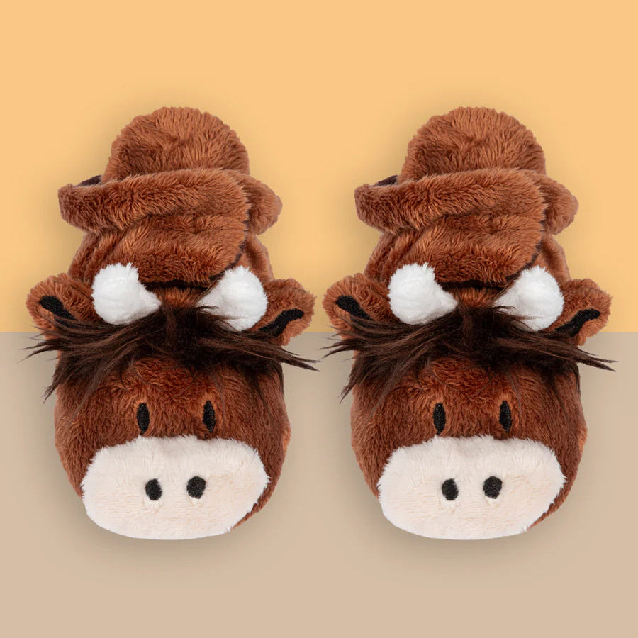 Pair of Neutral Highland Cow Booties with soft fleece lining, cow face detail and printed soles on beige background.