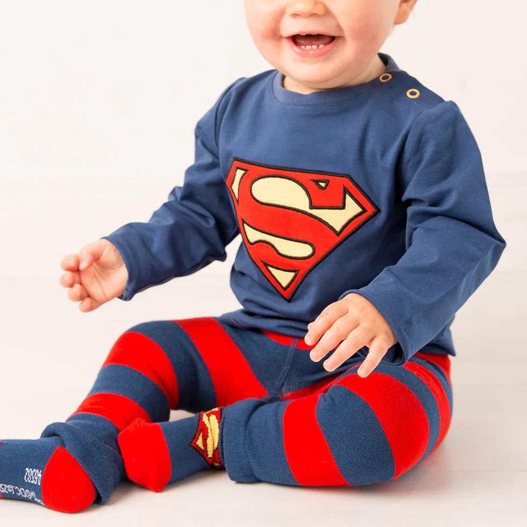 Smiling baby in full Superman™ outfit with matching long-sleeve top and Blade & Rose leggings, both featuring iconic Superman™ logo.