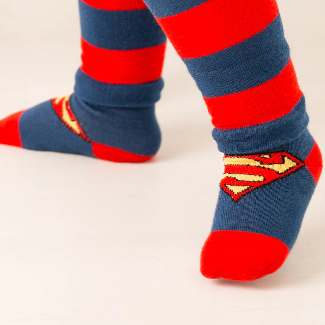 Toddler wearing Superman™ socks in blue and red with shield emblem, paired with matching superhero leggings.