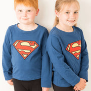 Two children wearing matching Superman™ blue tops with bold red and yellow logo.