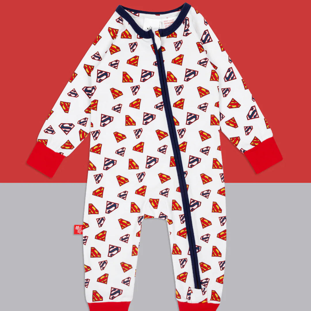 Flat lay of Superman Save The Day Zip Up Romper on red and grey background, featuring all-over Superman shield print, bright red cuffs, and navy zip.