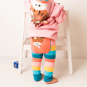 Back view of a toddler in Bonnie Highland Cow leggings with a bright floral Highland cow print.