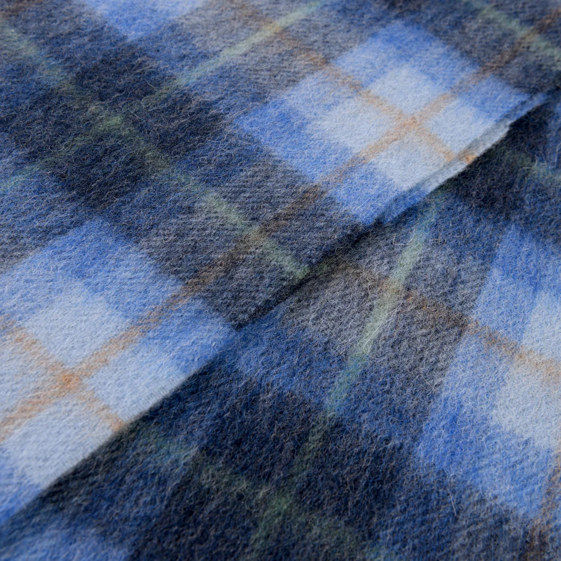 Close-up of blue tartan lambswool scarf fabric highlighting soft wool texture.