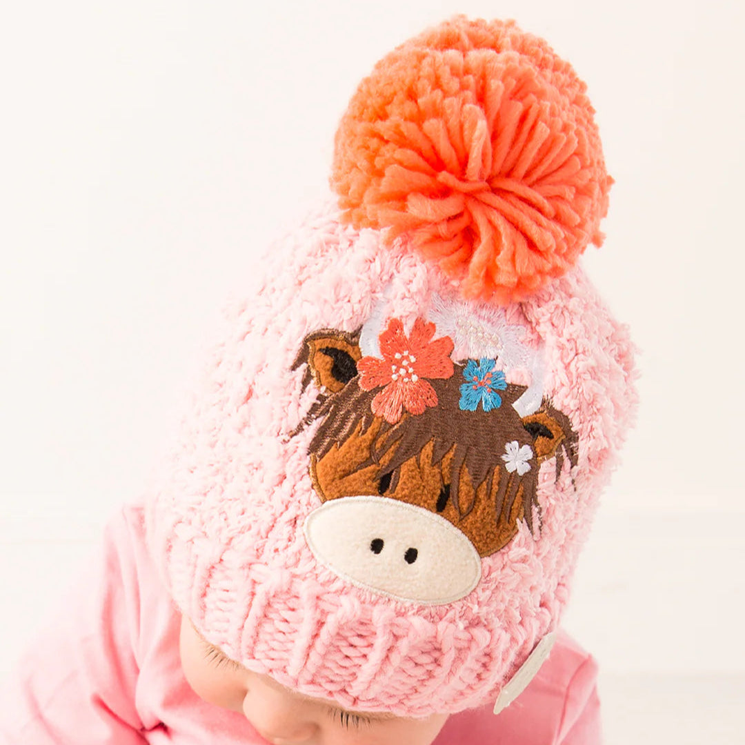 Baby wearing Bonnie Highland Cow Winter Hat – matching pink outfit with Highland cow design.